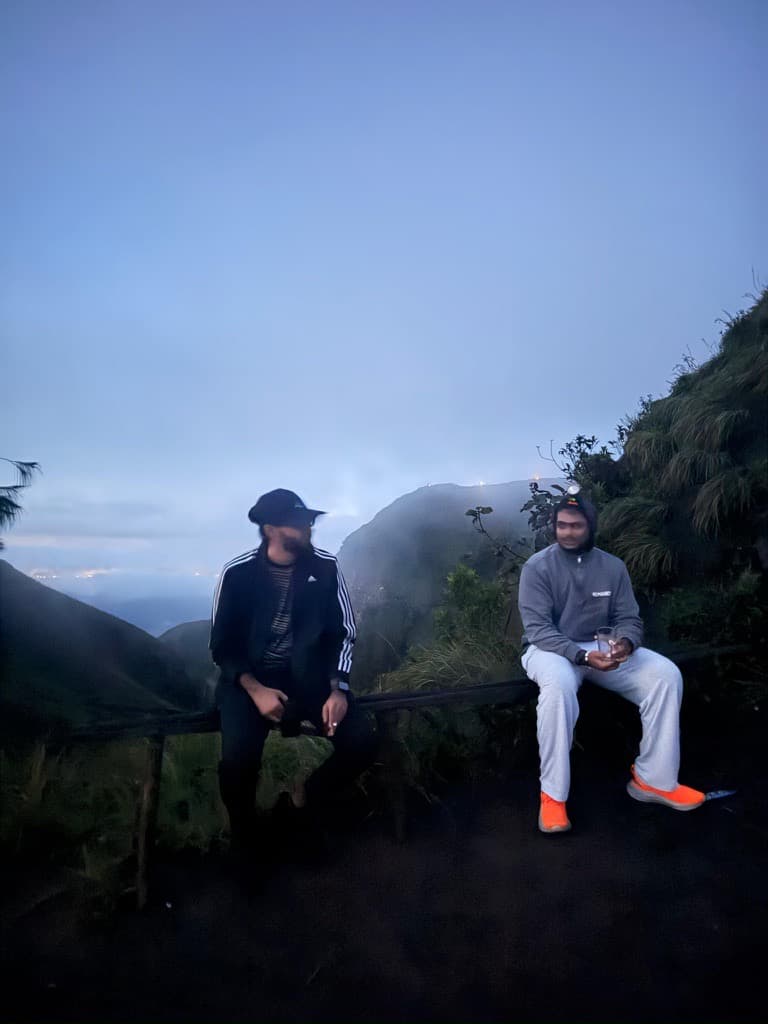 Two interns sitting on a railing in the blue dawn light waiting for sunrise on Mount Batur