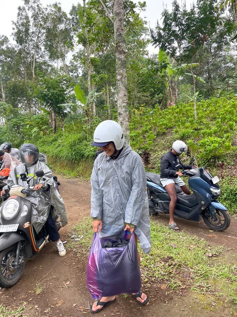 Interns in rain ponchos beside their scooters on a jungle track heading to Mount Batur